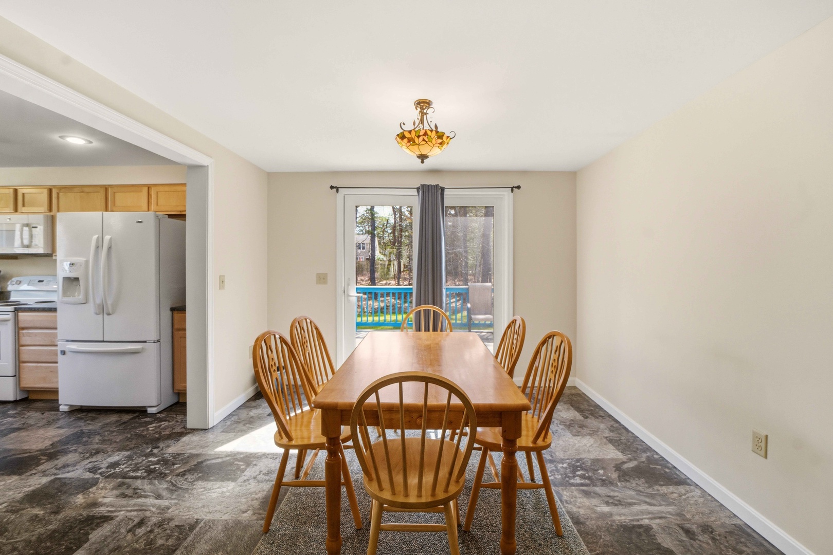 Gather around your warm wooden dining table for memorable meals, with a bright kitchen nearby and peaceful pool views through the window.