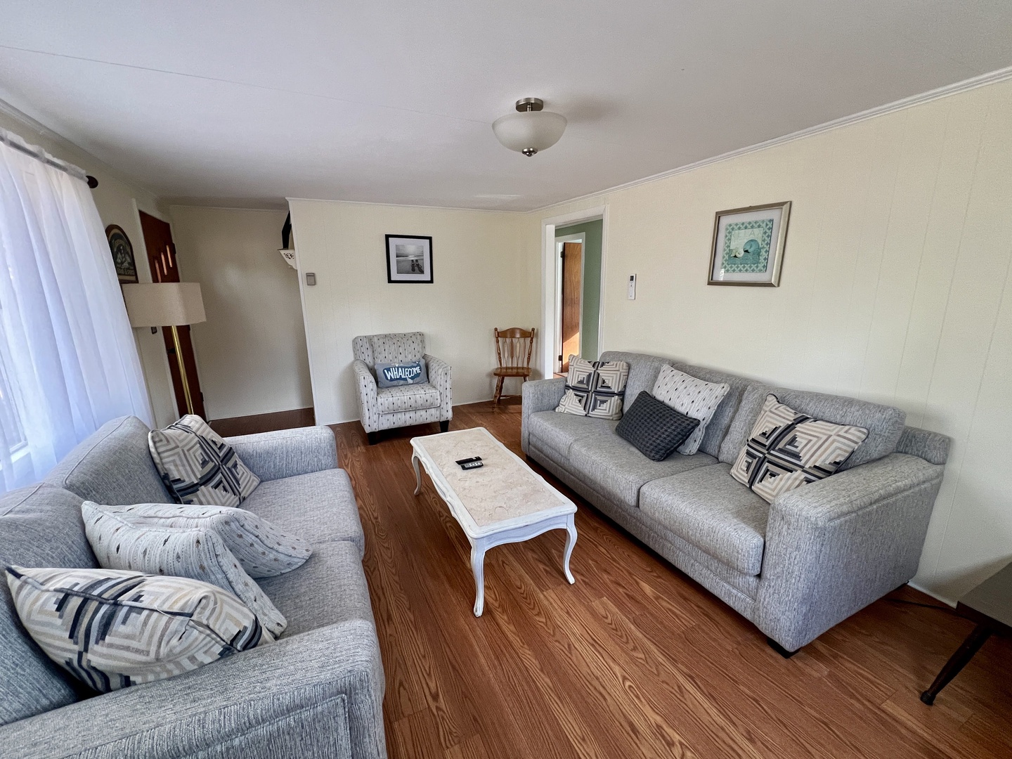 Settle into your comfortable living room with plush gray sofas, stylish throw pillows, and warm wood floors perfect for relaxing.