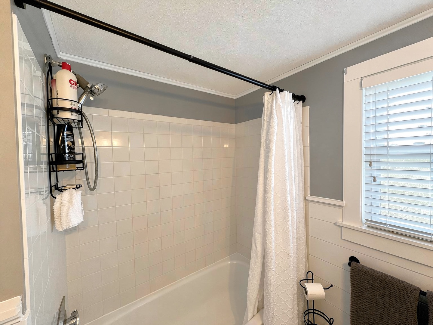 Step into a pristine bathroom where soothing gray walls meet crisp white tile. Your private shower awaits with plush towels and thoughtful toiletries ready for a refreshing rinse.