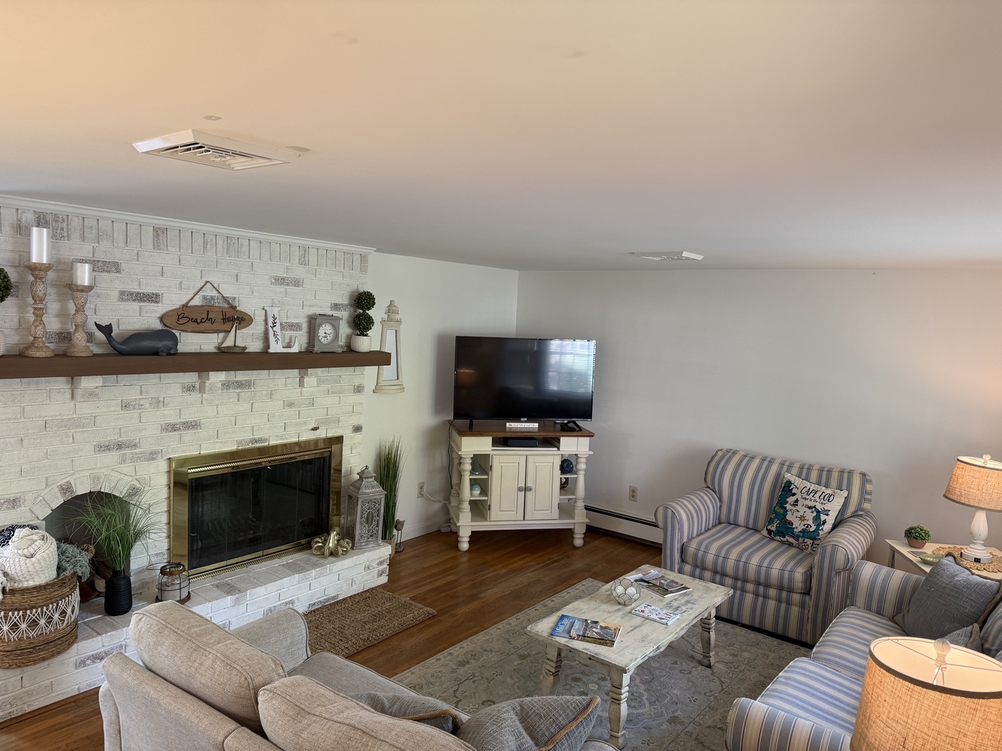 Sink into the soft striped couches by the warm fireplace, where rustic charm meets modern comfort with coastal touches throughout your relaxing retreat.