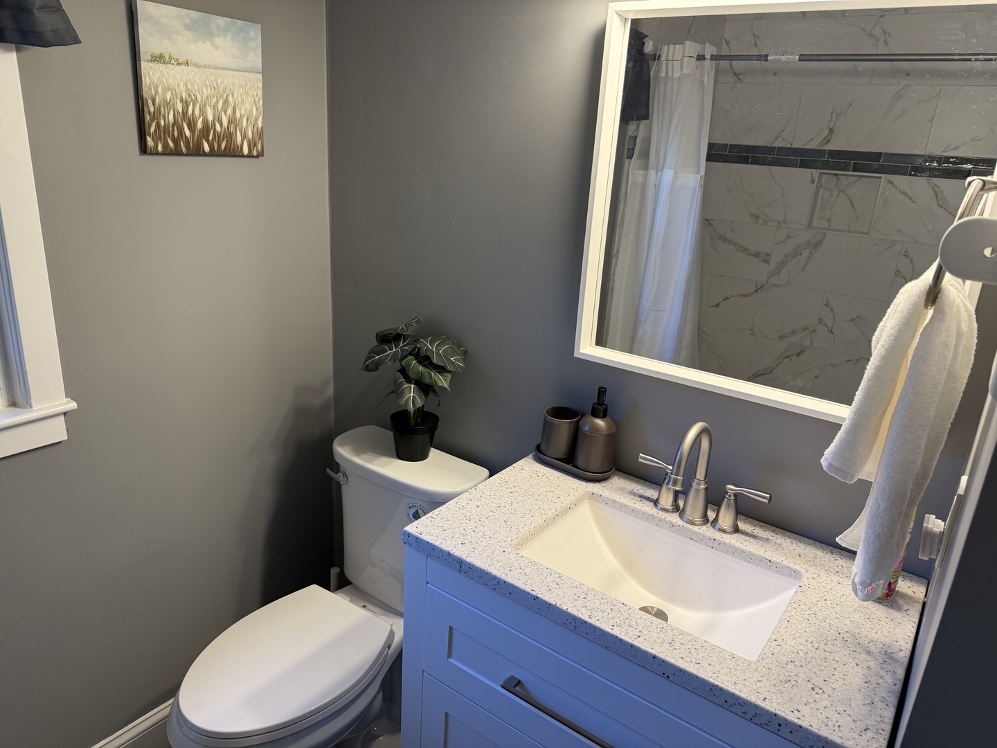 Refresh in your stylishly updated bathroom featuring modern fixtures, granite countertops, and thoughtful touches like fresh towels and greenery.