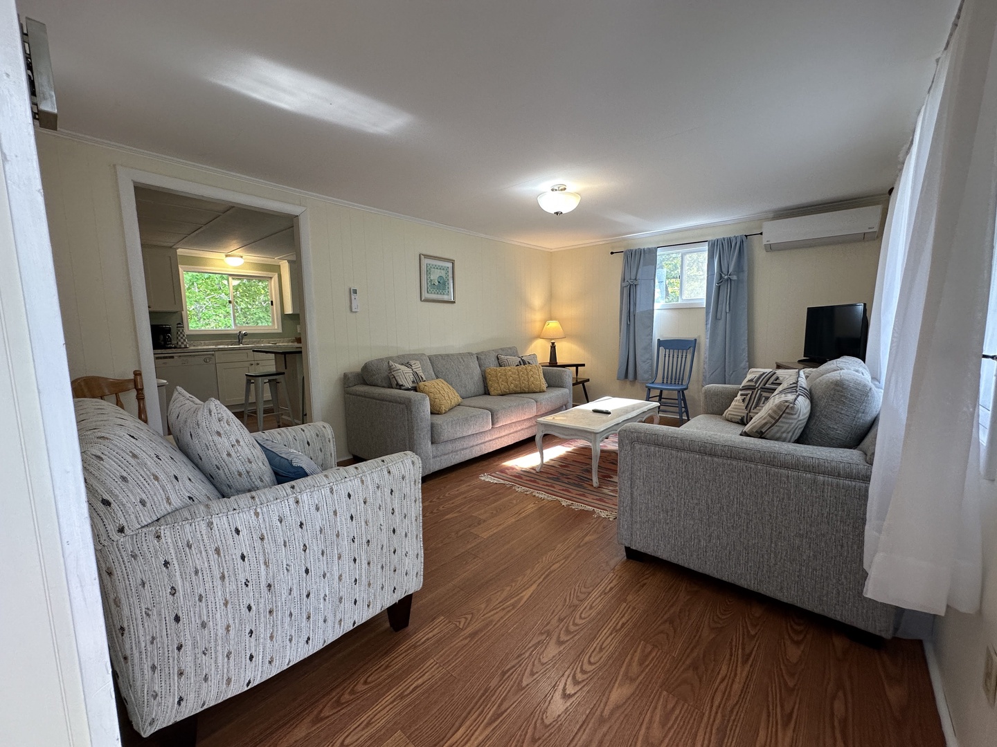 Sink into plush gray sofas in your spacious living room, where warm lighting and hardwood floors create perfect comfort for movie nights.