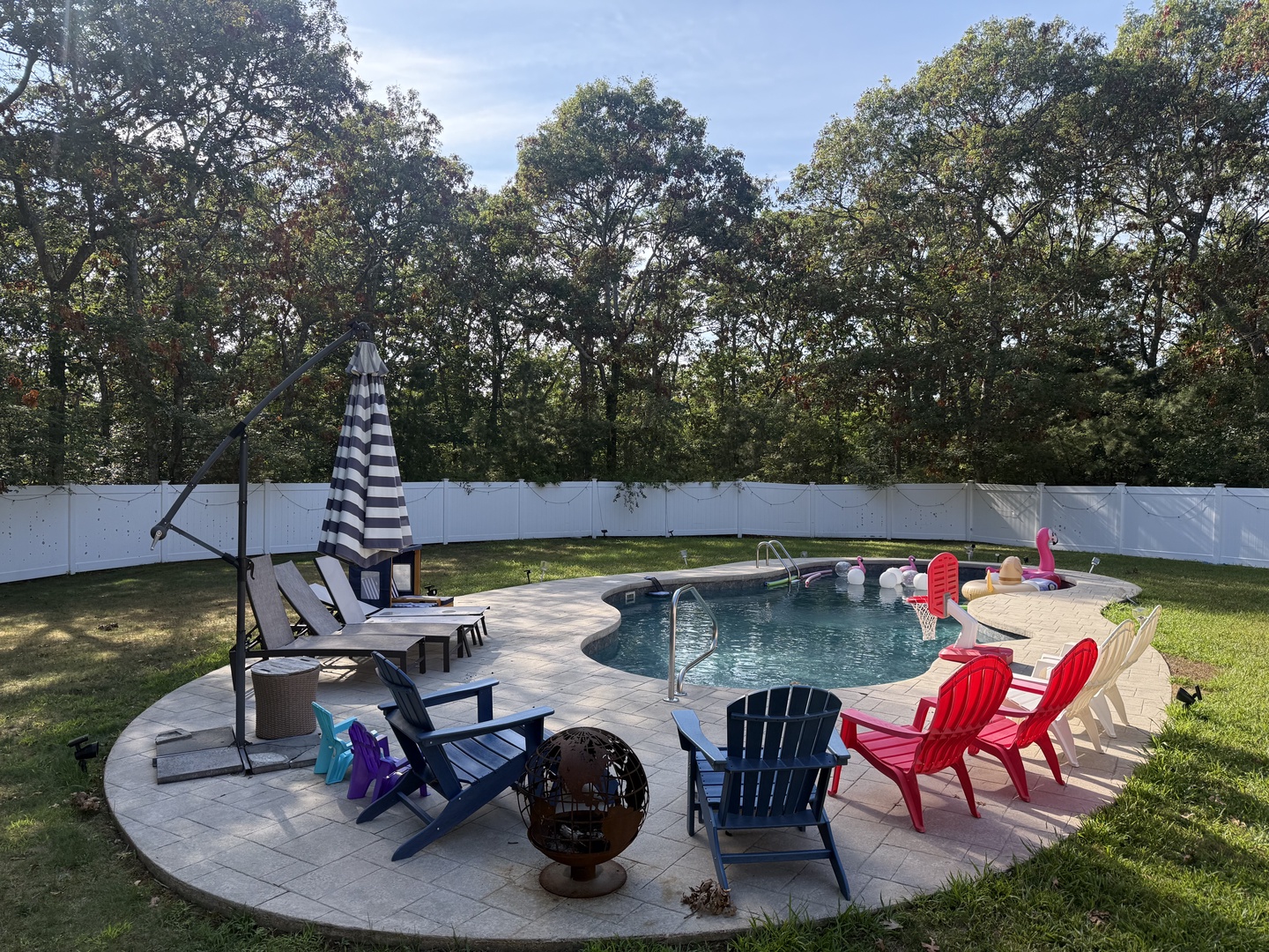 Dive into your private pool oasis surrounded by colorful Adirondack chairs, perfect for sunny afternoons and poolside relaxation in your secluded backyard retreat.