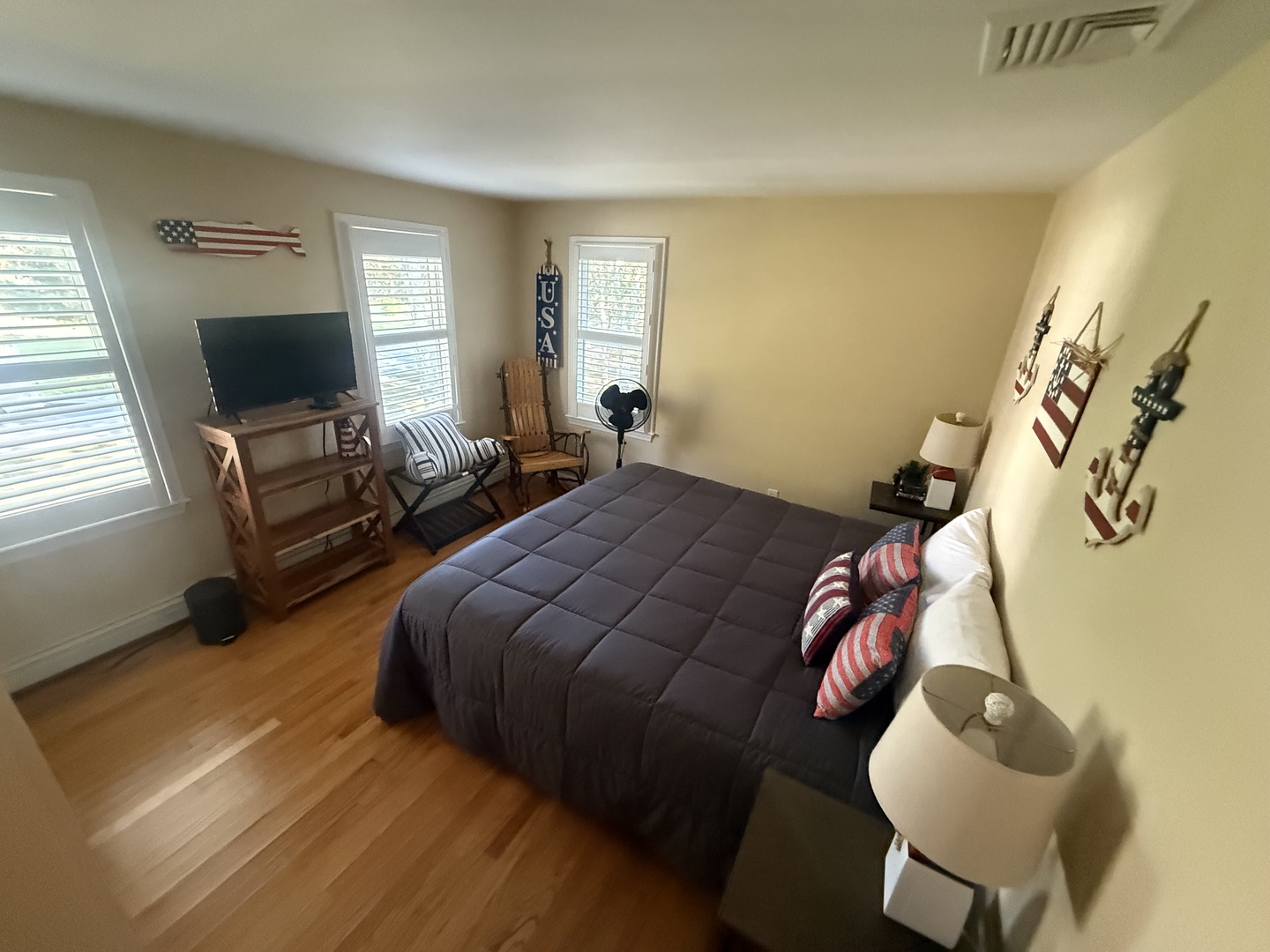 Unwind in your cozy bedroom featuring warm hardwood floors, comfortable seating, and cheerful natural light streaming through multiple windows.