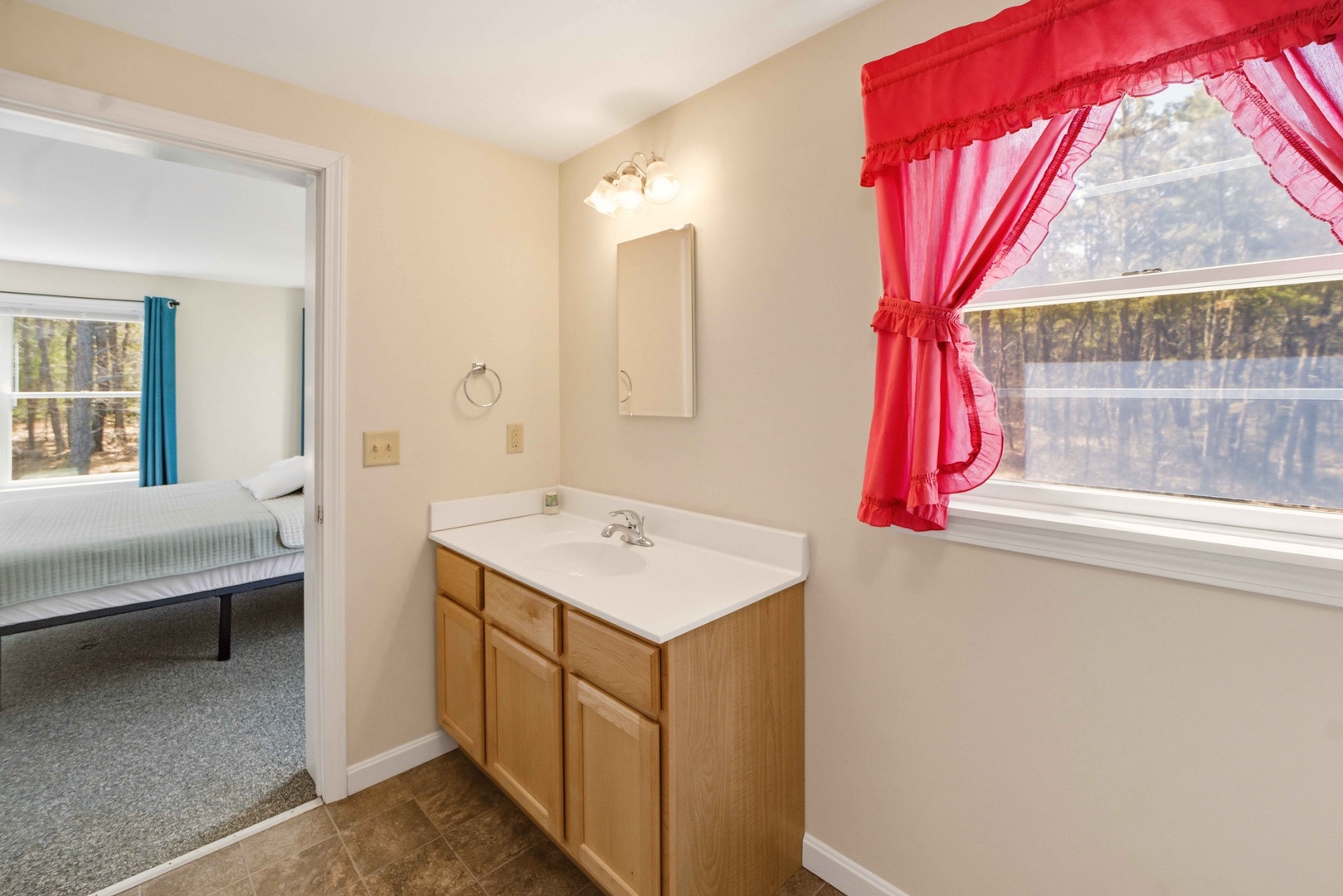 Your private bathroom features a spacious vanity and charming red curtains that frame peaceful forest views.
