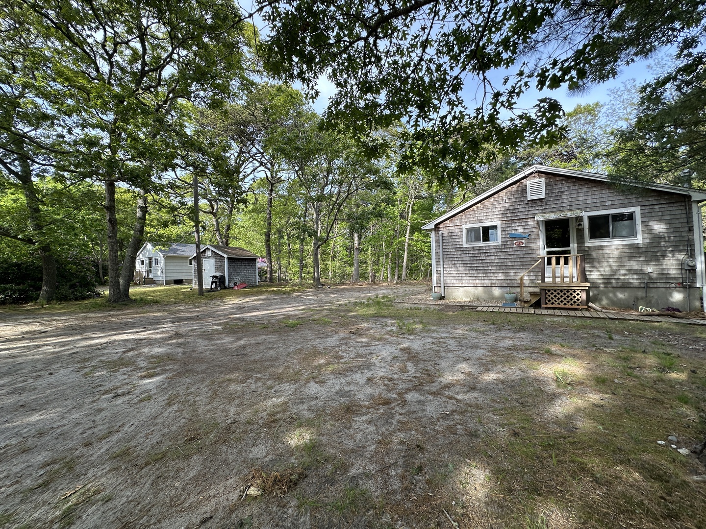 Charming weathered-shingle cottages nestled among towering trees with spacious parking for a peaceful woodland retreat.