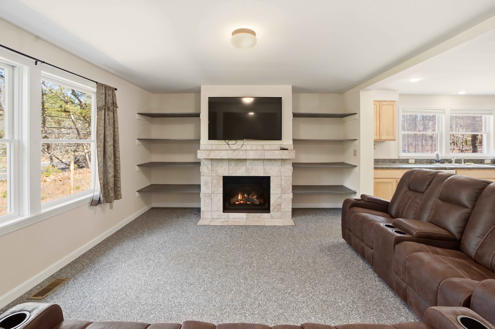Cozy up in your spacious living room featuring a stunning fireplace, built-in shelving, and comfortable leather seating perfect for relaxing evenings.