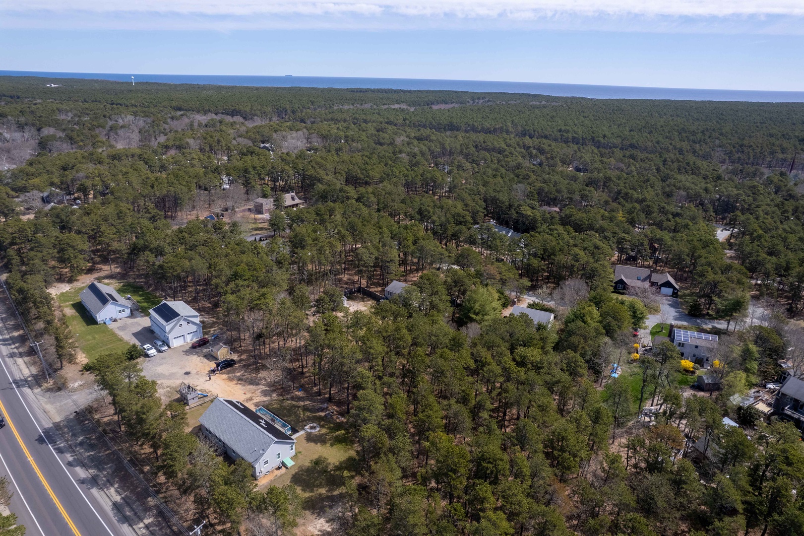 Aerial view showcasing the property's peaceful wooded setting and coastal proximity in this charming residential area.