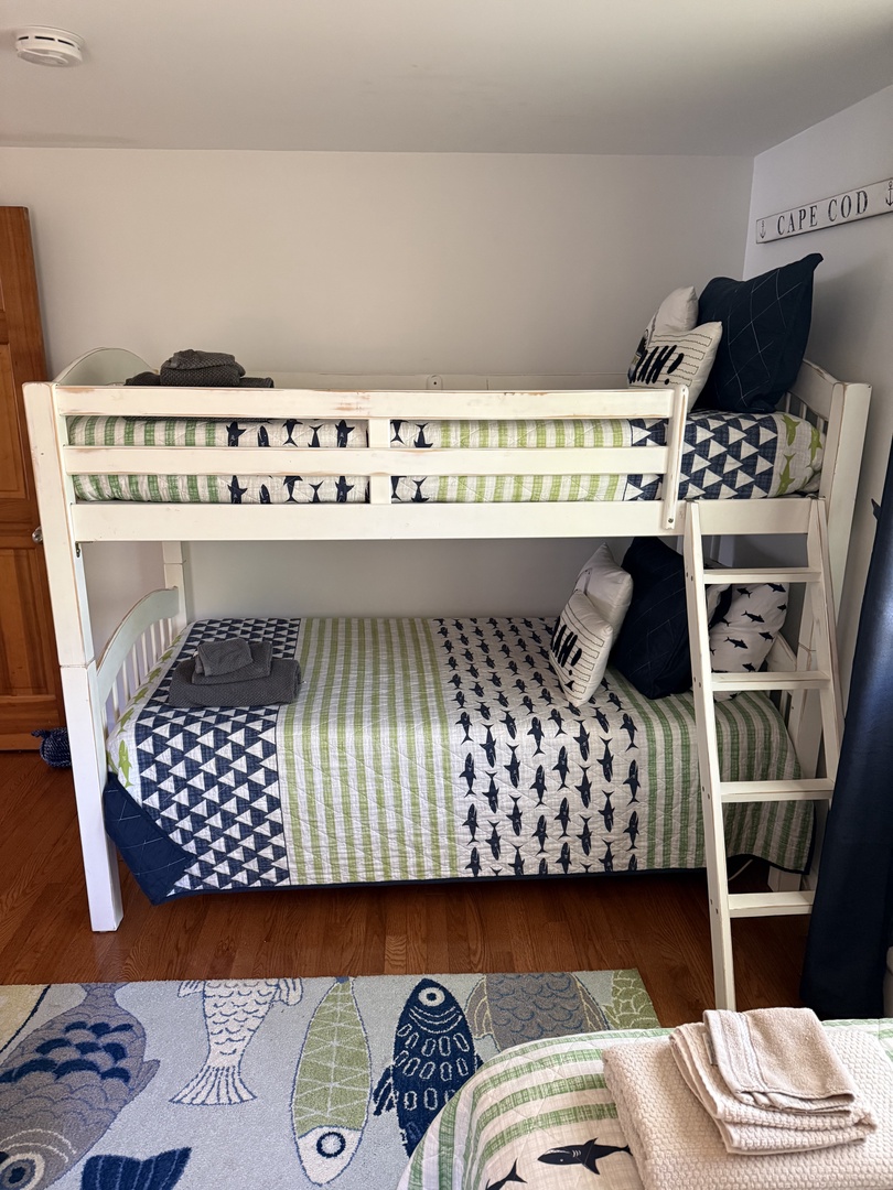 Your kids will love this fun nautical bedroom with playful shark bedding and a sturdy bunk bed—perfect for bedtime stories and sweet dreams.