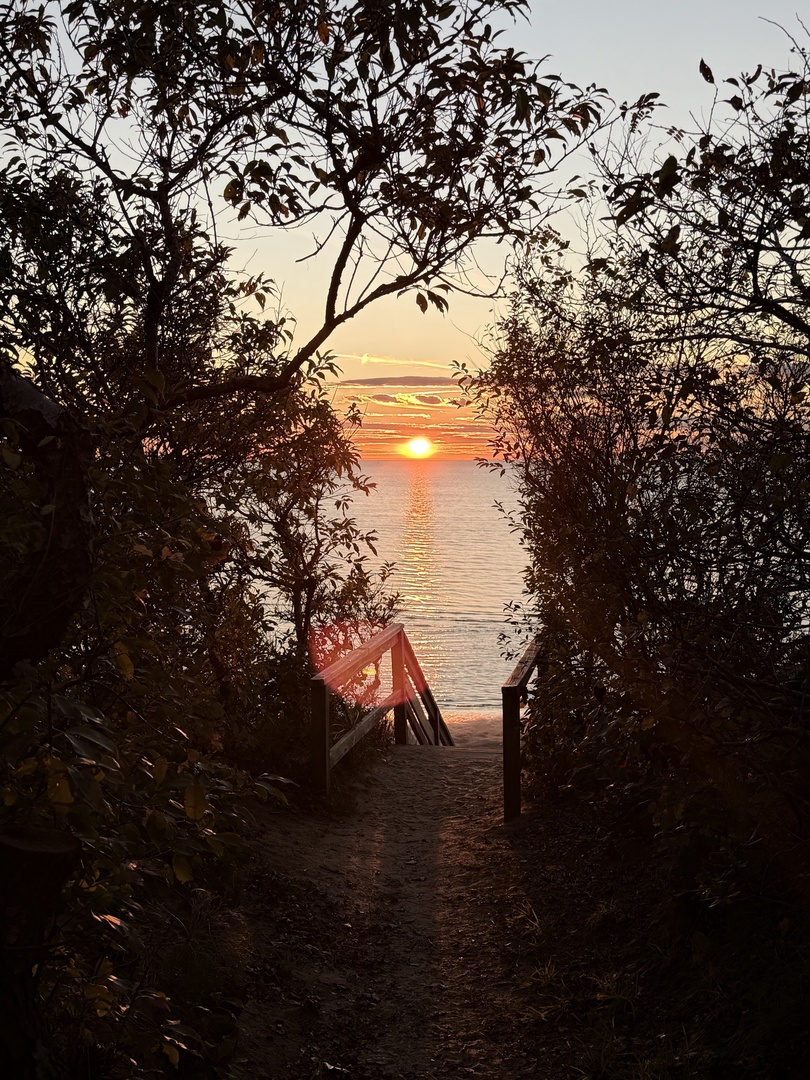 Golden sunrise illuminates the peaceful waterfront, creating a serene backdrop for the property's natural setting.