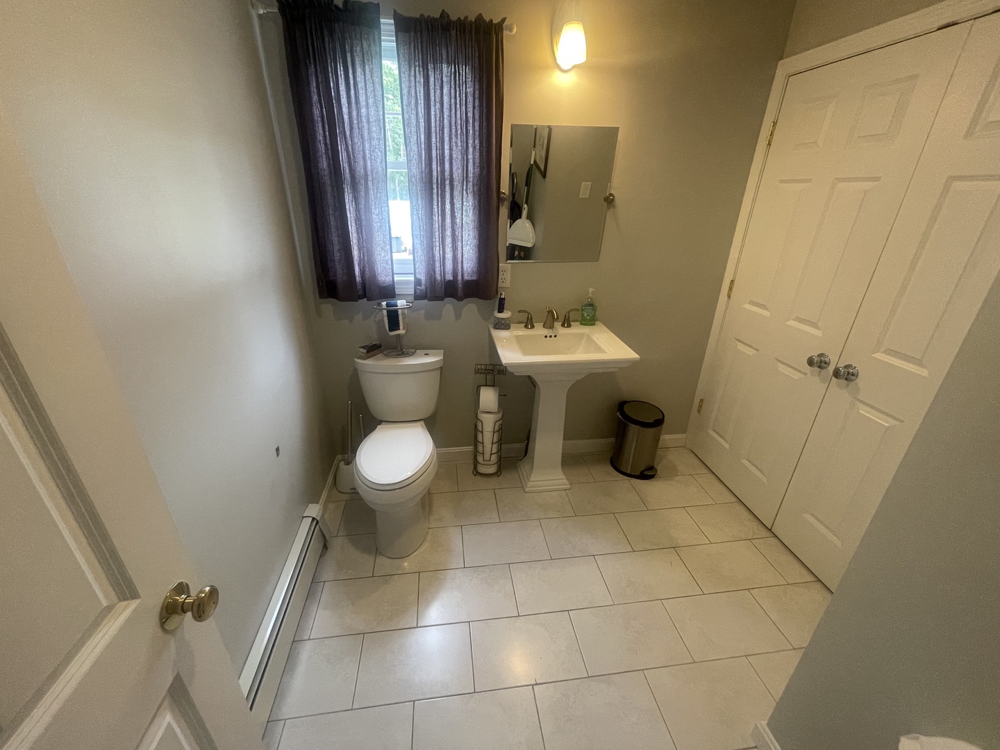 Step into your private bathroom featuring elegant tile floors, modern pedestal sink, and natural light filtering through curtained windows.