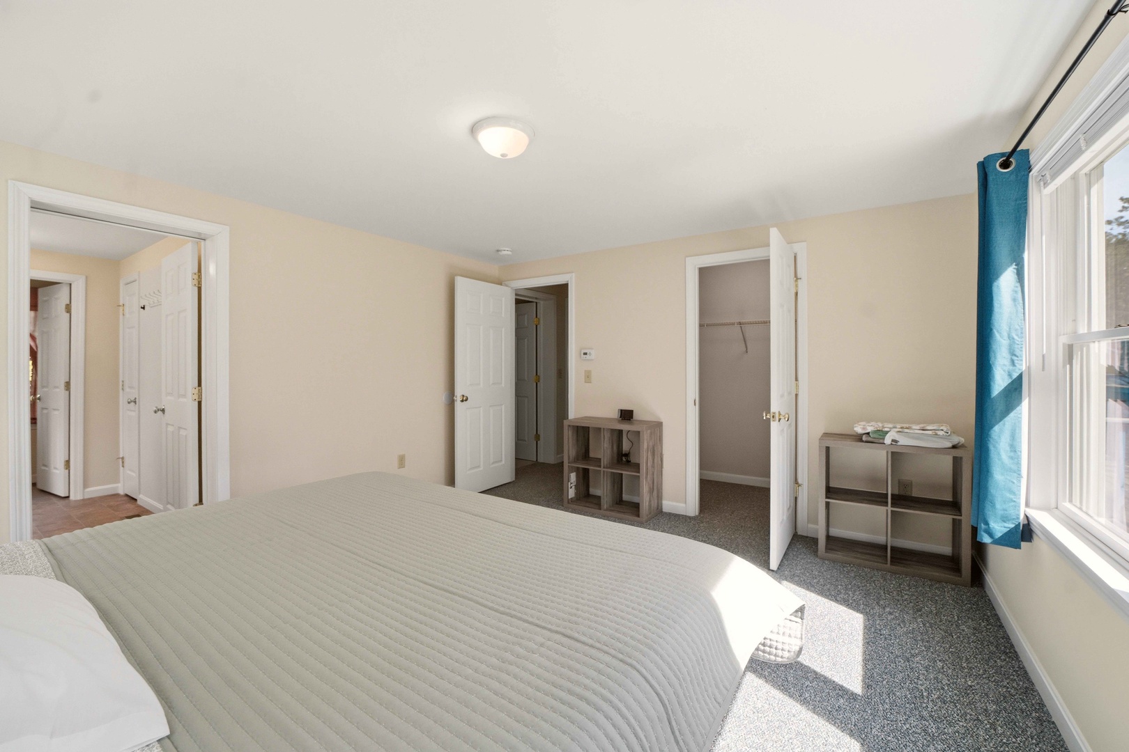 Your bright bedroom features comfortable bedding and thoughtful storage space, with natural light streaming through large windows to create a peaceful retreat.