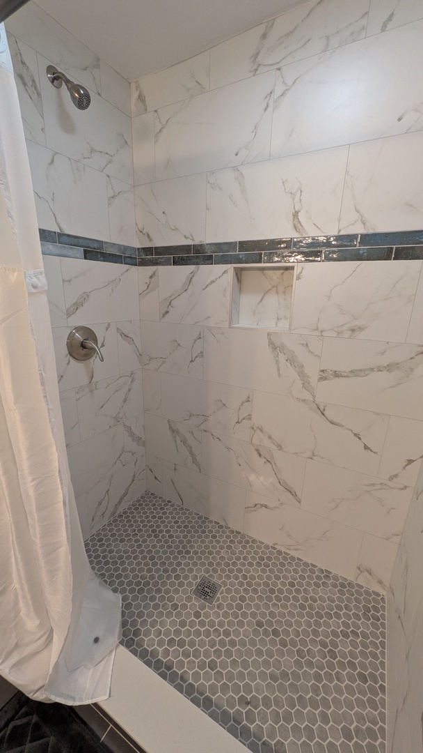 Step into your luxurious marble-inspired shower featuring beautiful tile work and a built-in niche for your essentials.