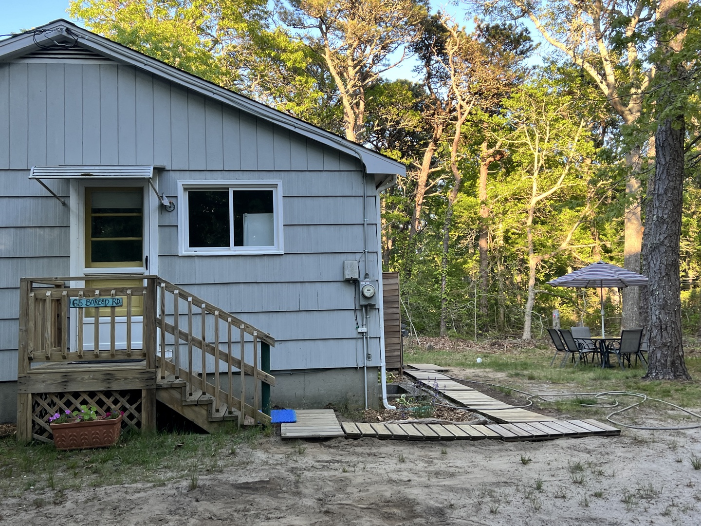Charming cottage nestled among towering trees offers peaceful woodland retreat with outdoor seating area and private deck for morning coffee.