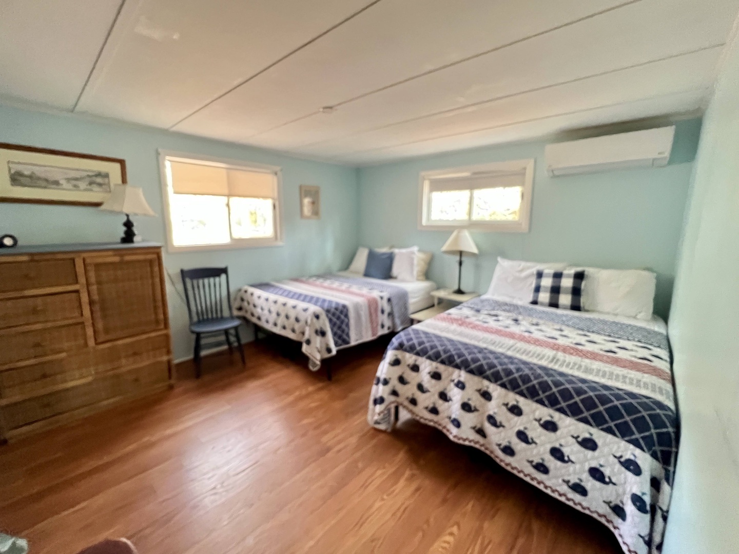 Unwind in your tranquil twin bedroom with soft coastal colors, warm hardwood floors, and cheerful natural light streaming through charming windows.