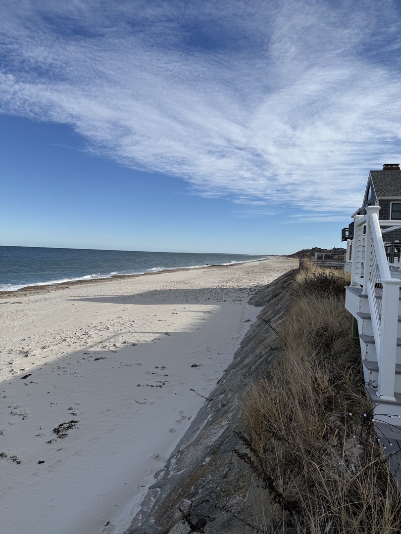 Pristine beachfront location with white sand stretching along crystal-clear waters and charming coastal buildings nearby.