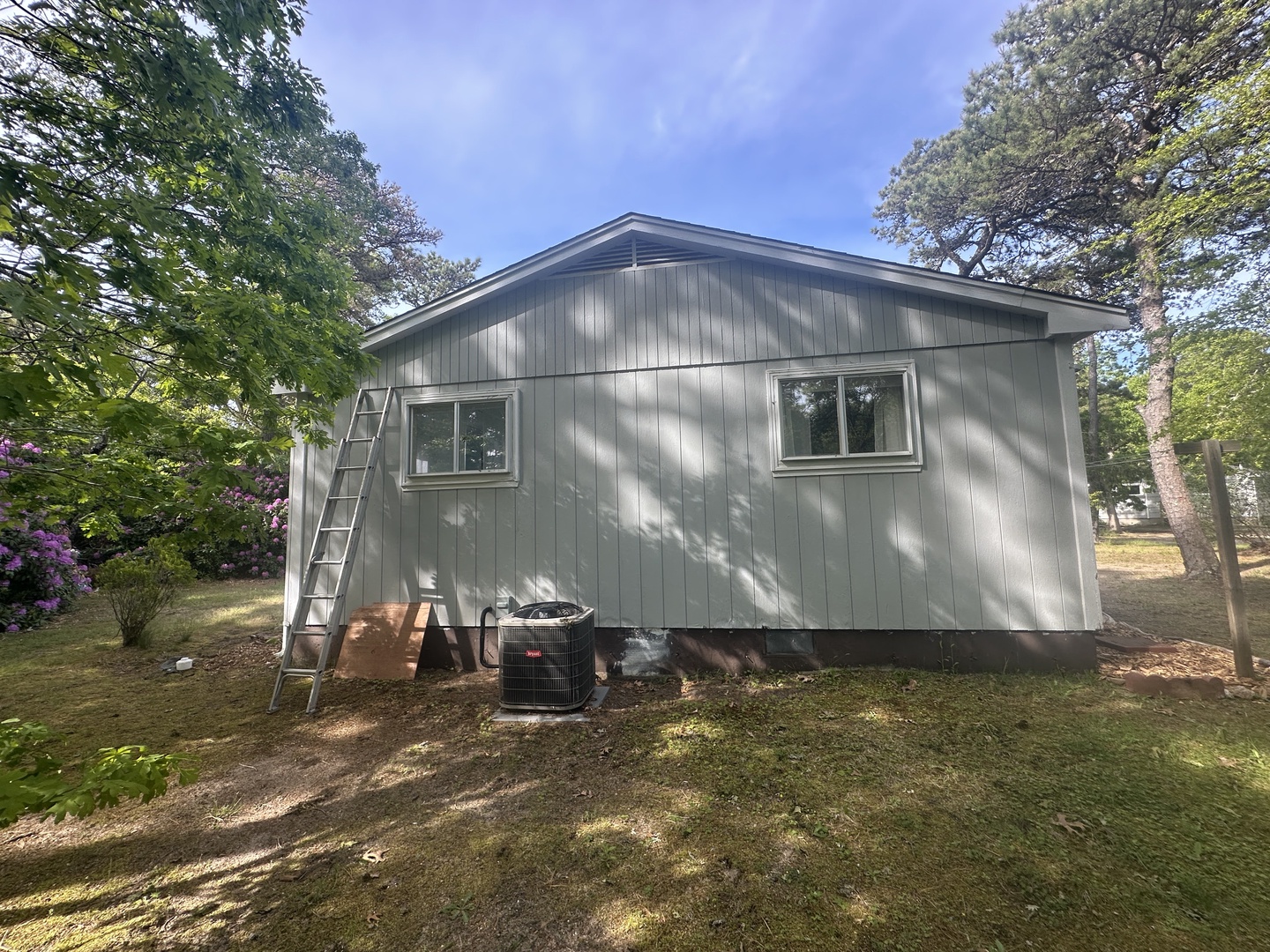 Charming cottage nestled among mature trees with blooming gardens, offering a peaceful retreat surrounded by nature's beauty.