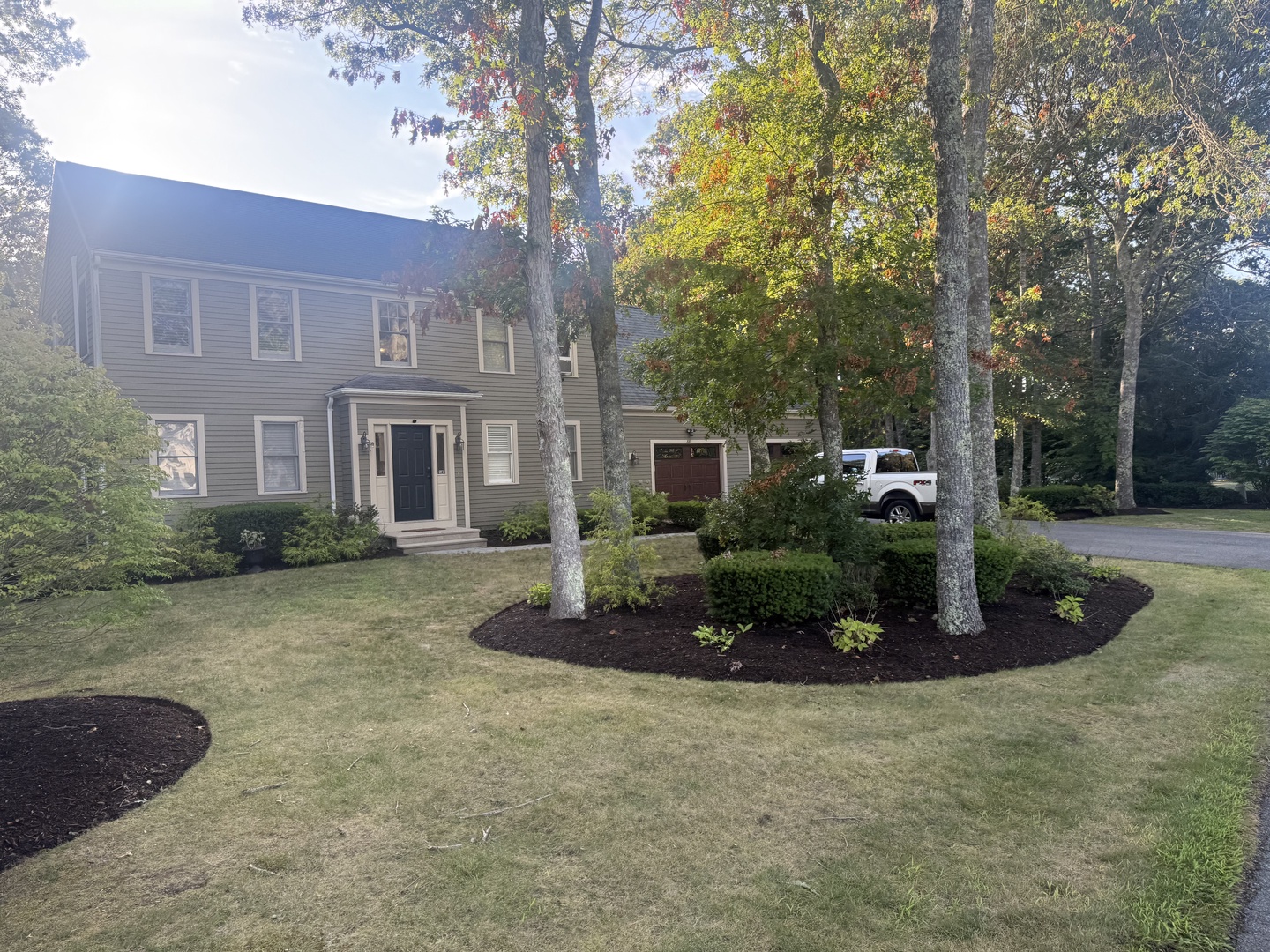 Charming two-story colonial home nestled among mature trees with beautifully landscaped grounds and convenient parking access.