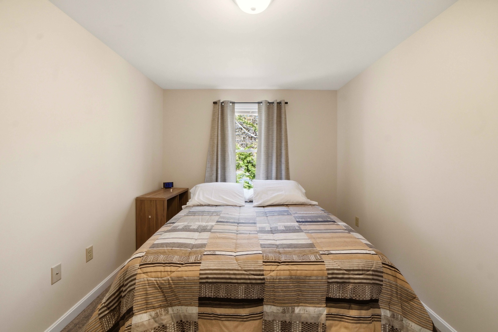 Your cozy bedroom awaits with fresh linens and a peaceful garden view through soft curtains.