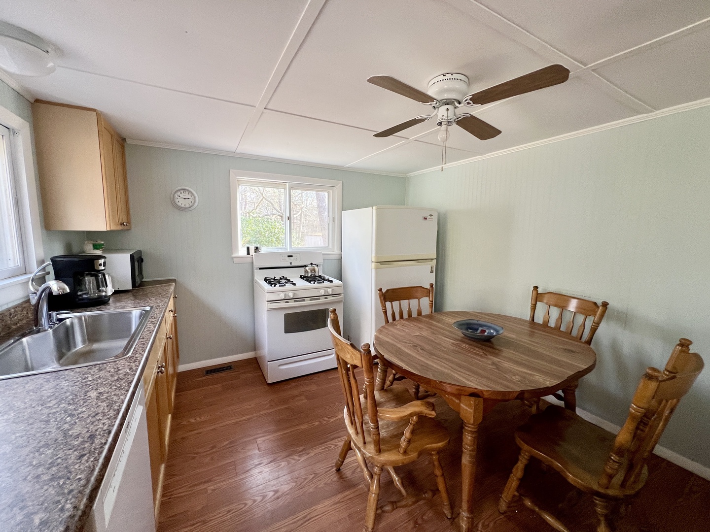 Your comfortable kitchen and dining space features everything you need - full appliances, warm wood table, and cooling ceiling fan for cozy meals together.