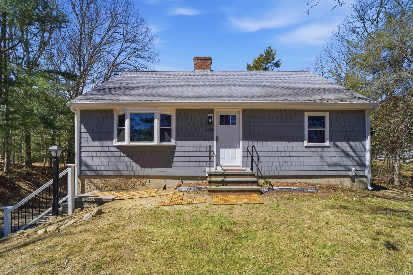 Charming cottage exterior with classic shingle siding and peaceful wooded surroundings in the neighborhood.