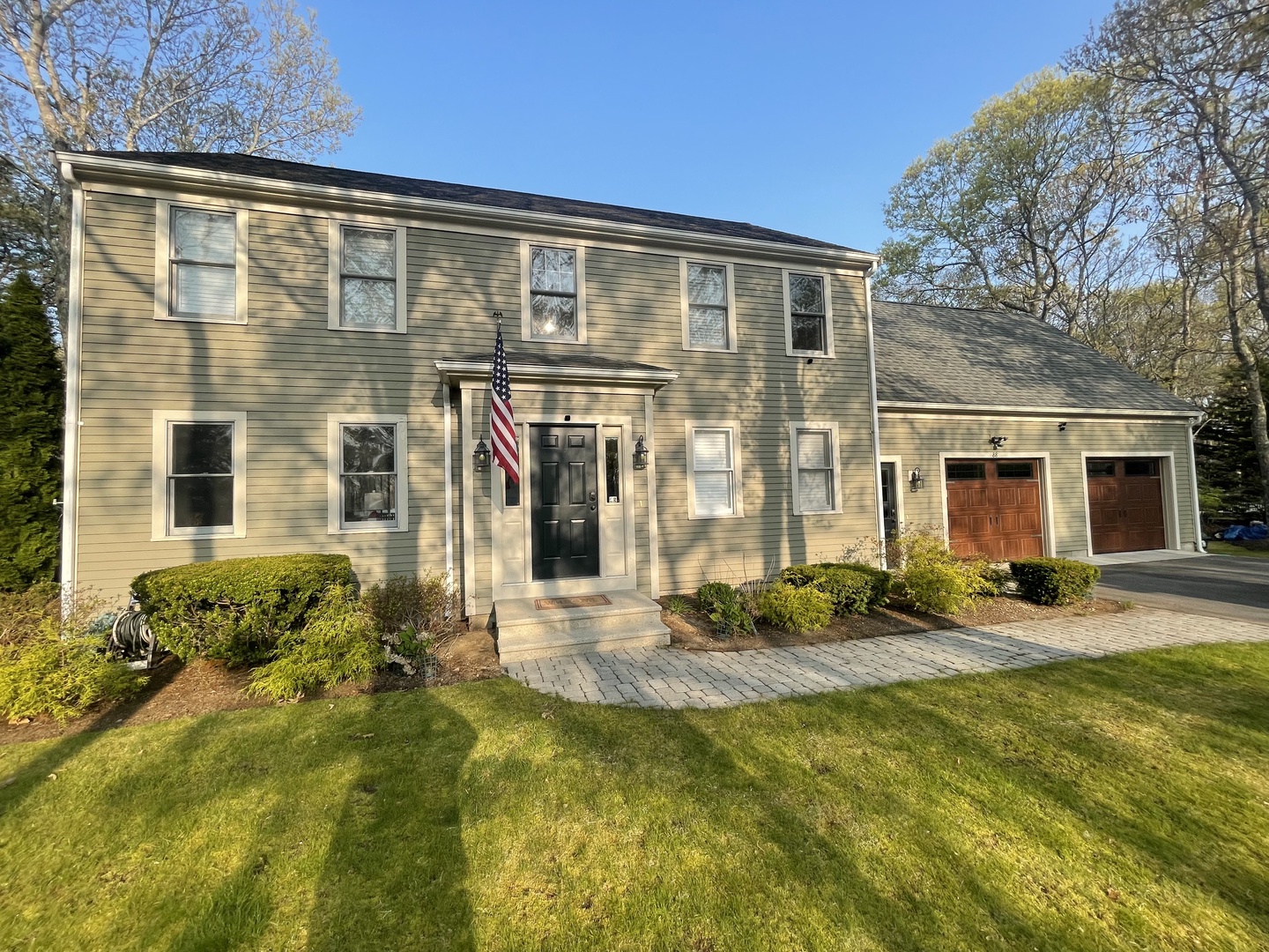 Charming colonial home with manicured landscaping, and welcoming front entrance surrounded by mature trees.