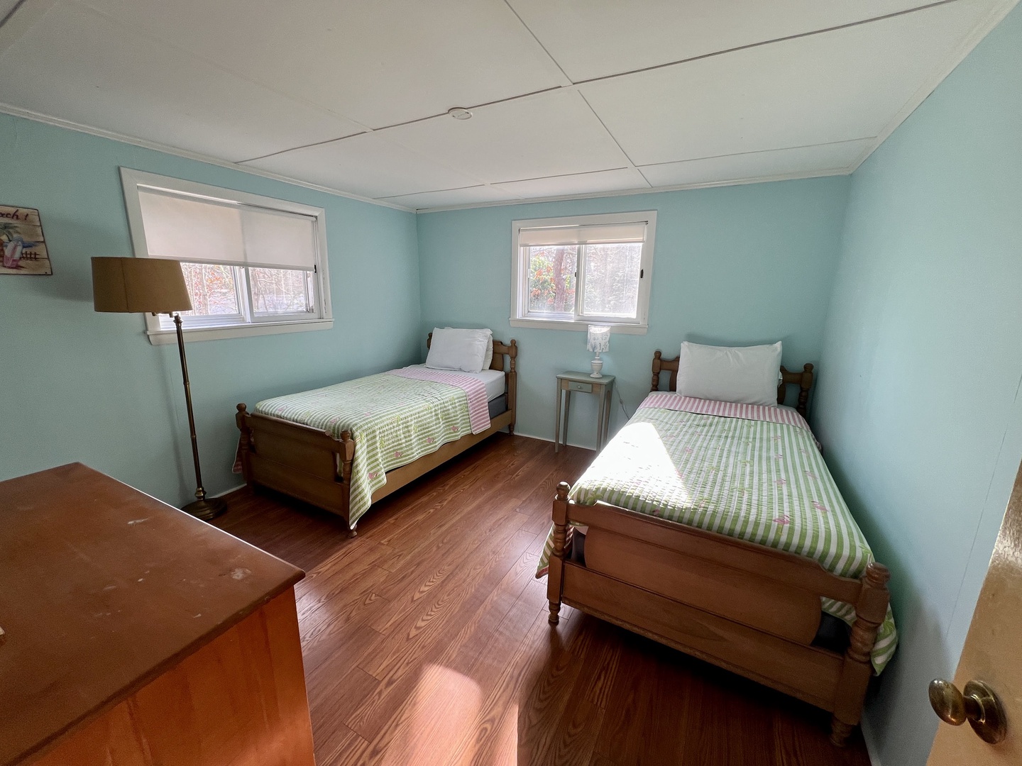 Sleep peacefully in this twin bedroom featuring two comfortable wooden beds with fresh linens and soothing aqua walls.