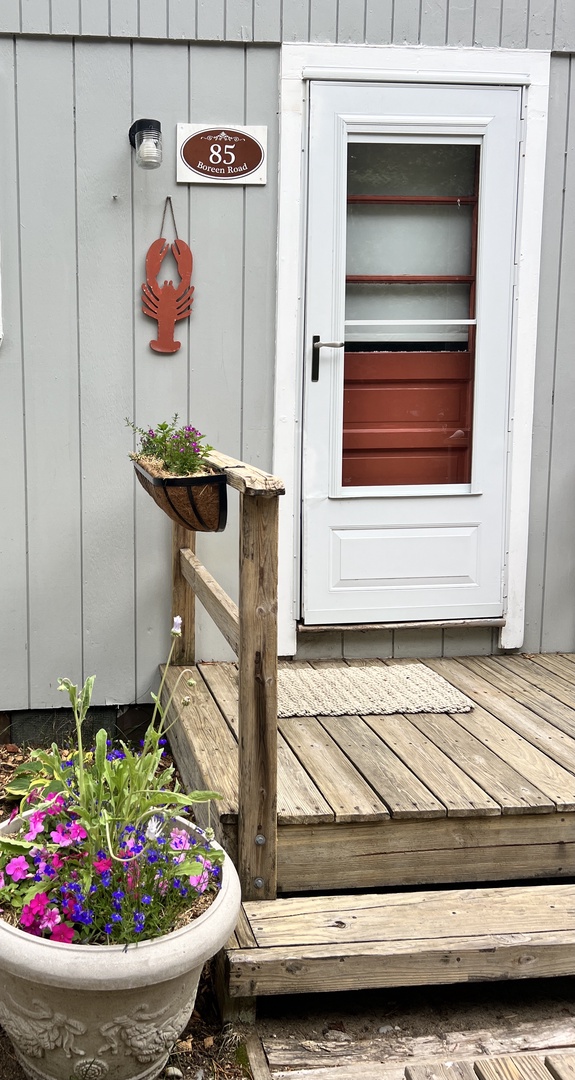 Charming entrance welcomes you with coastal flair—lobster decor and blooming flowers create the perfect seaside getaway mood.