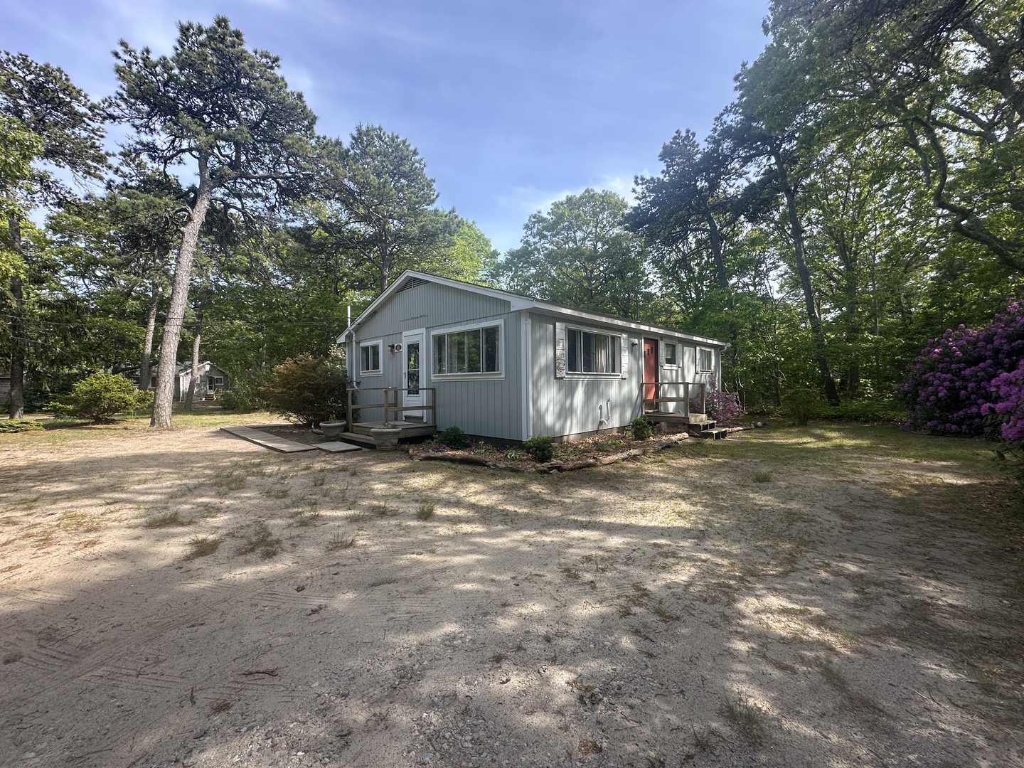 Modern retreat nestled in a private wooded setting with mature trees and seasonal blooms surrounding the property.