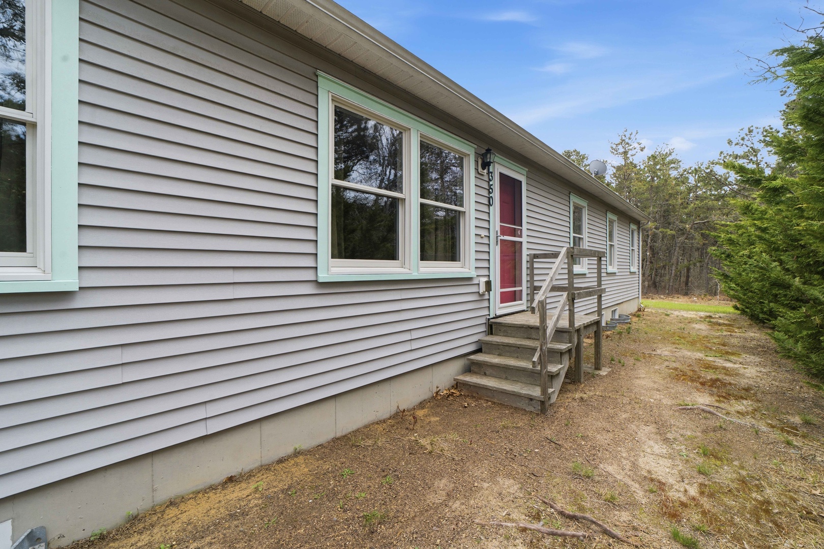 A charming single-story home with a welcoming red front door set among peaceful wooded surroundings.