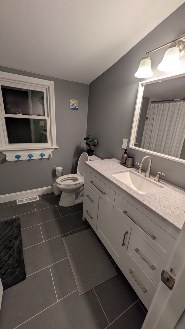 Step into your beautifully renovated bathroom with modern vanity, quartz counters, and stylish gray tile flooring for your comfort.