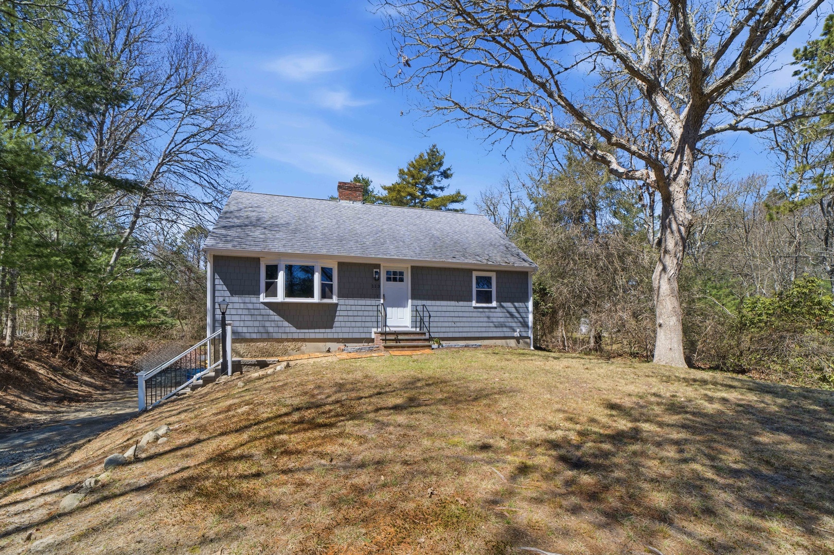A charming single-story cottage nestled on a peaceful wooded lot, offering tranquil privacy surrounded by mature trees.