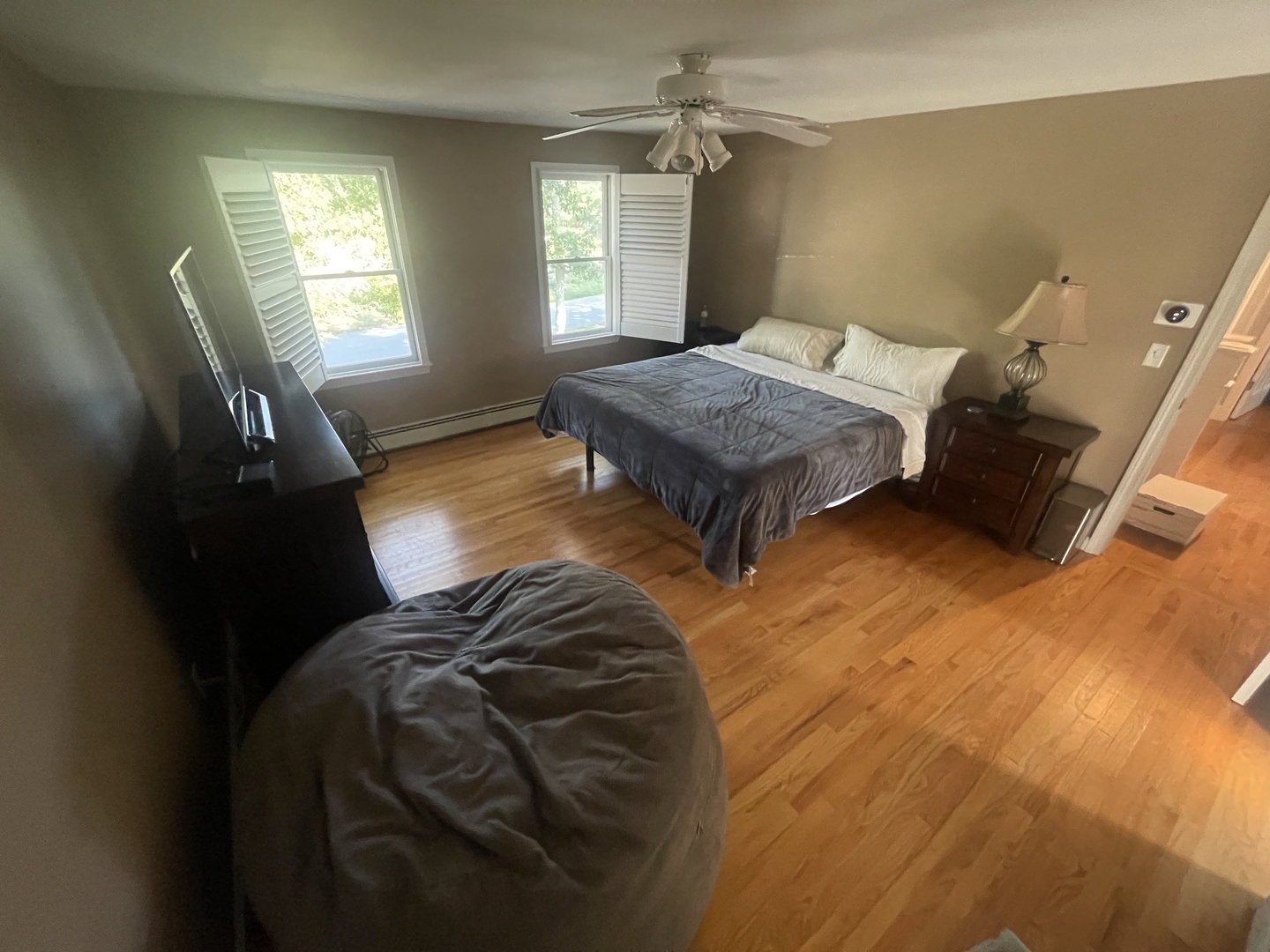 Relax in your spacious bedroom with gleaming hardwood floors, plush bedding, and natural light streaming through large windows.