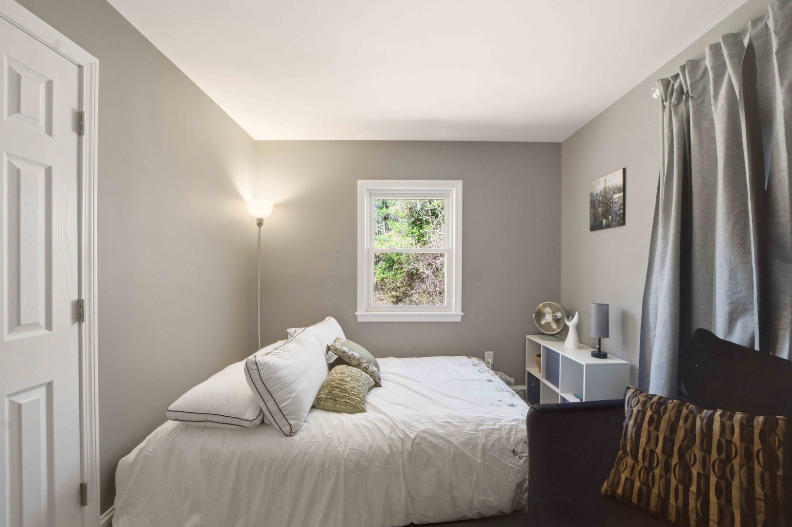 Sink into crisp white linens in your serene bedroom, where soft gray walls and natural light create the perfect retreat for restful nights.