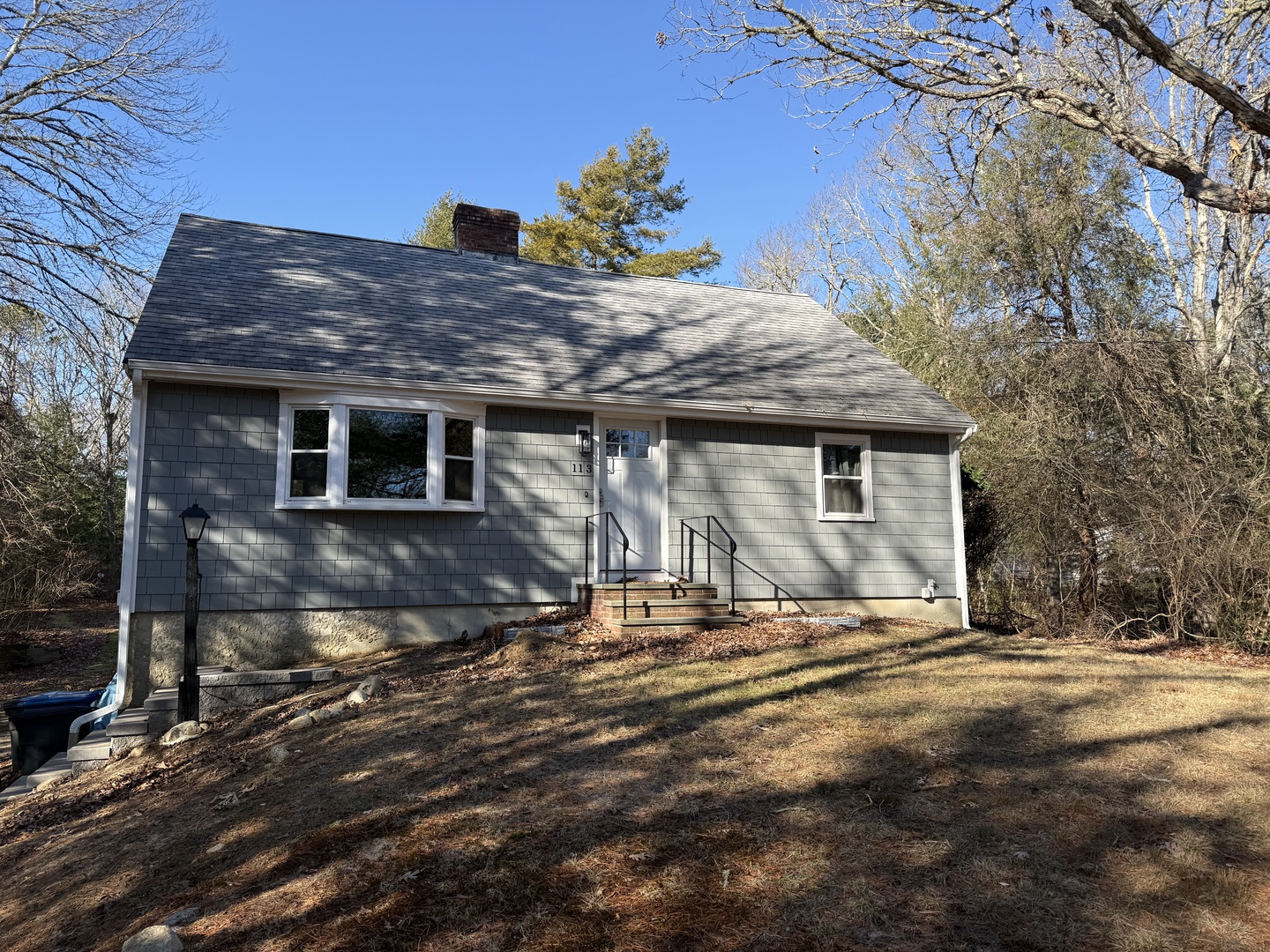 Charming Cape Cod-style home nestled among mature trees on a peaceful residential lot with ample natural surroundings.