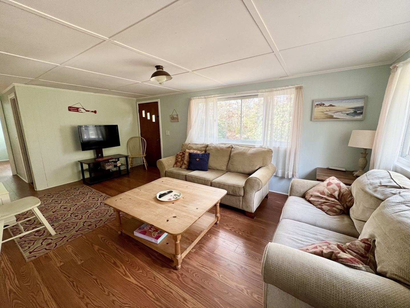 Unwind in your cozy living room with plush seating, natural light streaming through large windows, and rustic charm perfect for relaxing.