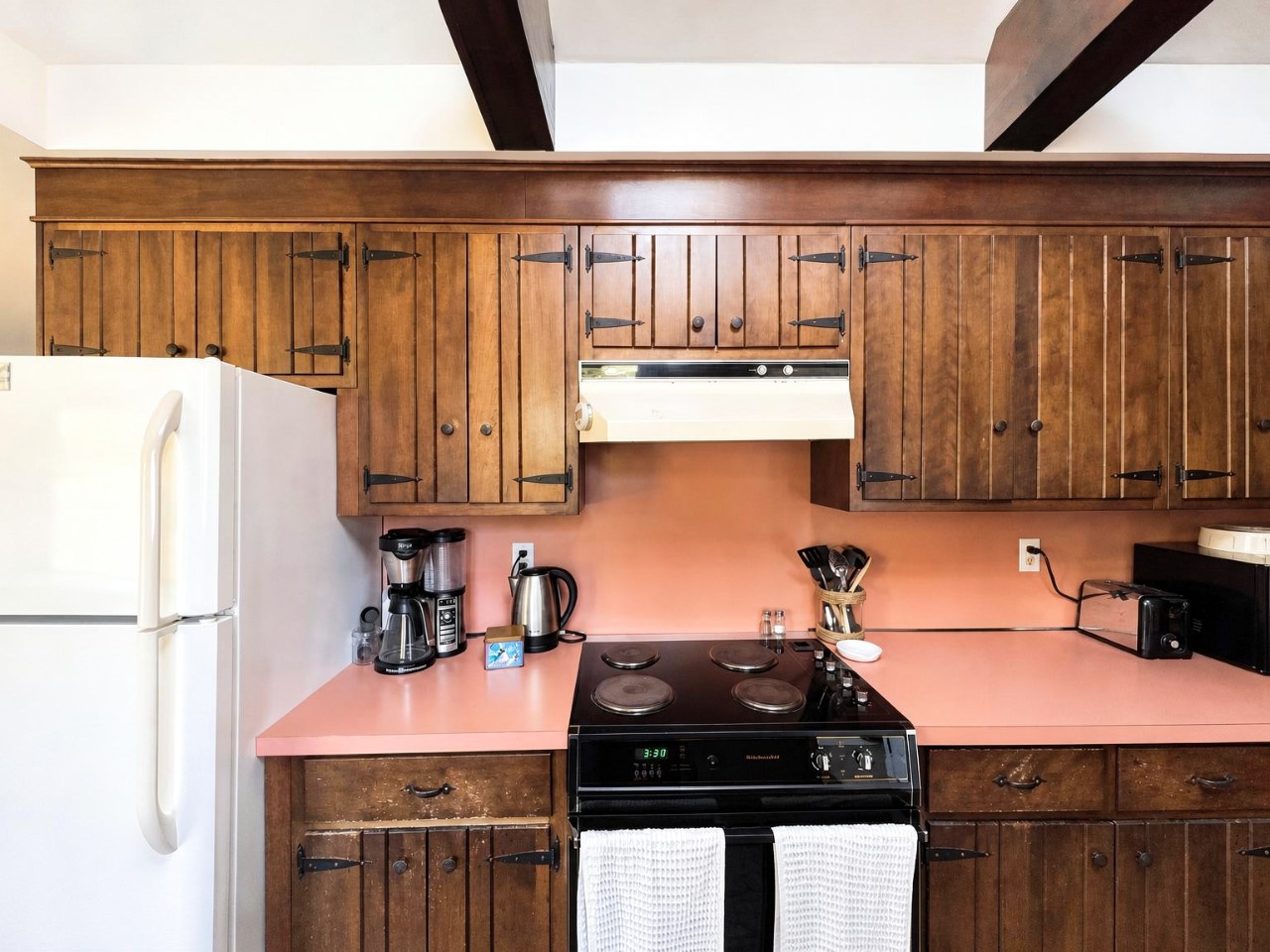 Your fully-equipped kitchen features charming wood cabinetry, all the essentials for cooking, and a unique pink countertop that adds a warm, retro vibe to your stay.