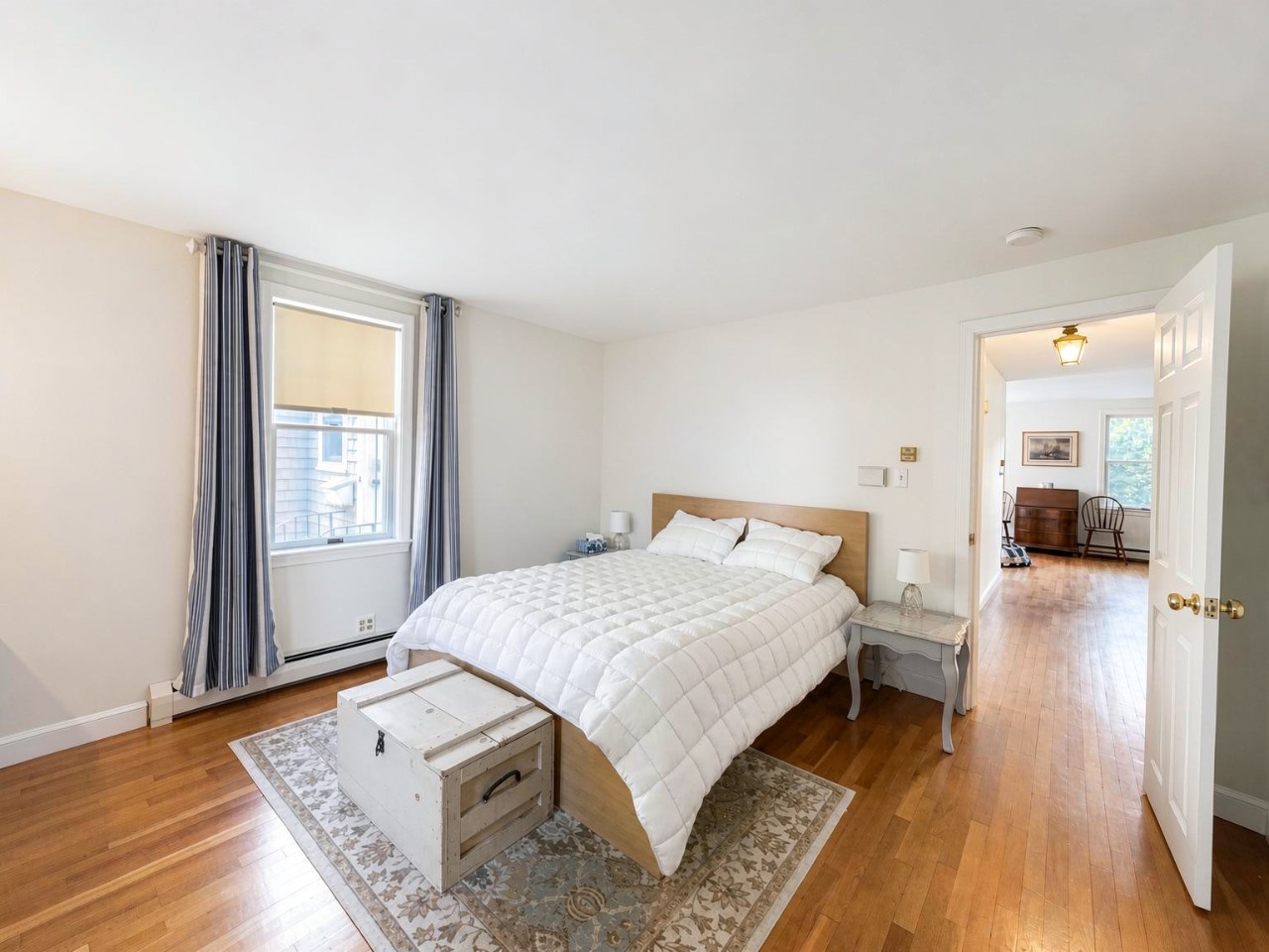 You'll sleep peacefully in this bright, airy bedroom featuring plush linens, warm hardwood floors, and soft natural light. The inviting space connects seamlessly to other areas of the home.