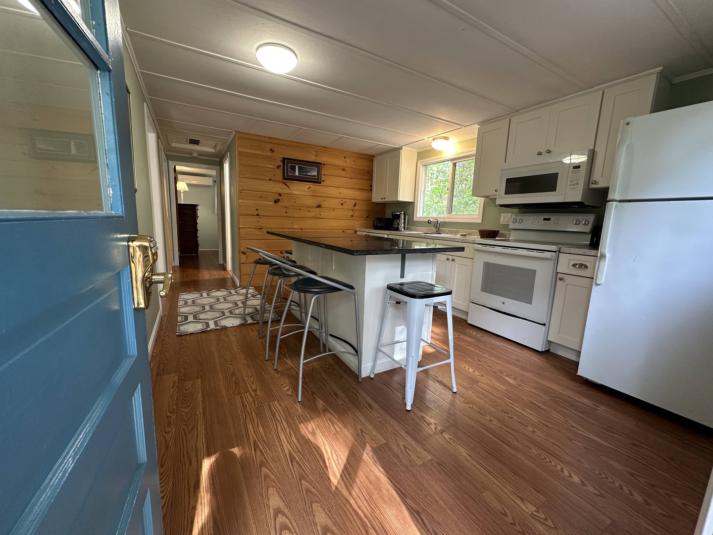 Your fully equipped kitchen features white appliances, an island for casual meals, and warm wood accents creating a cozy cooking space.