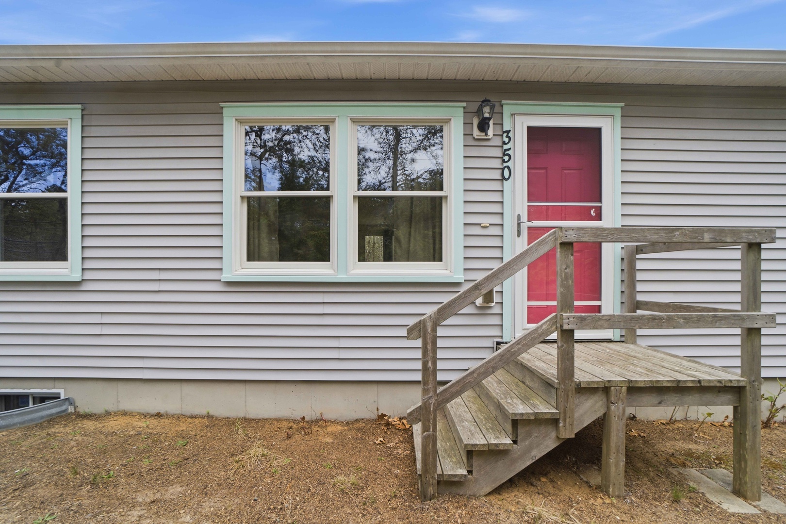 A welcoming property entrance with red door and wooden stairs leading to your comfortable home away from home.