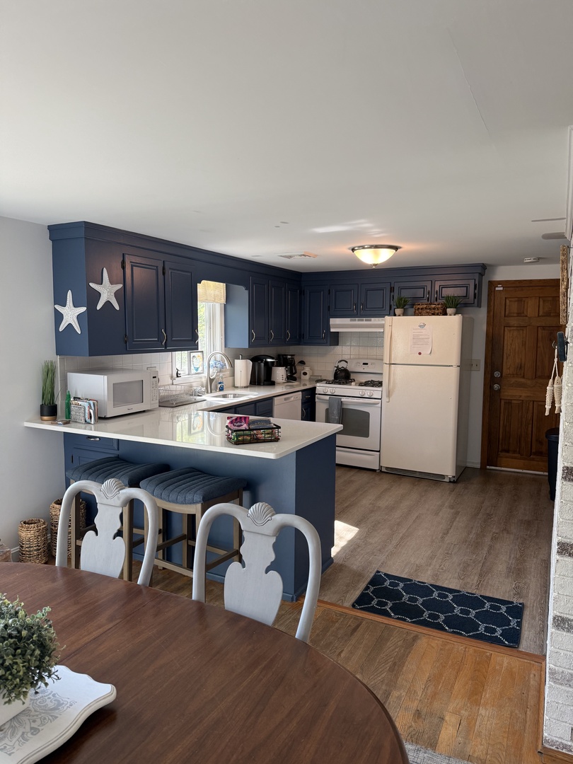 Your bright and welcoming kitchen features coastal-themed cabinetry, modern appliances, and a cozy dining nook—perfect for preparing meals and sharing stories over coffee each morning.