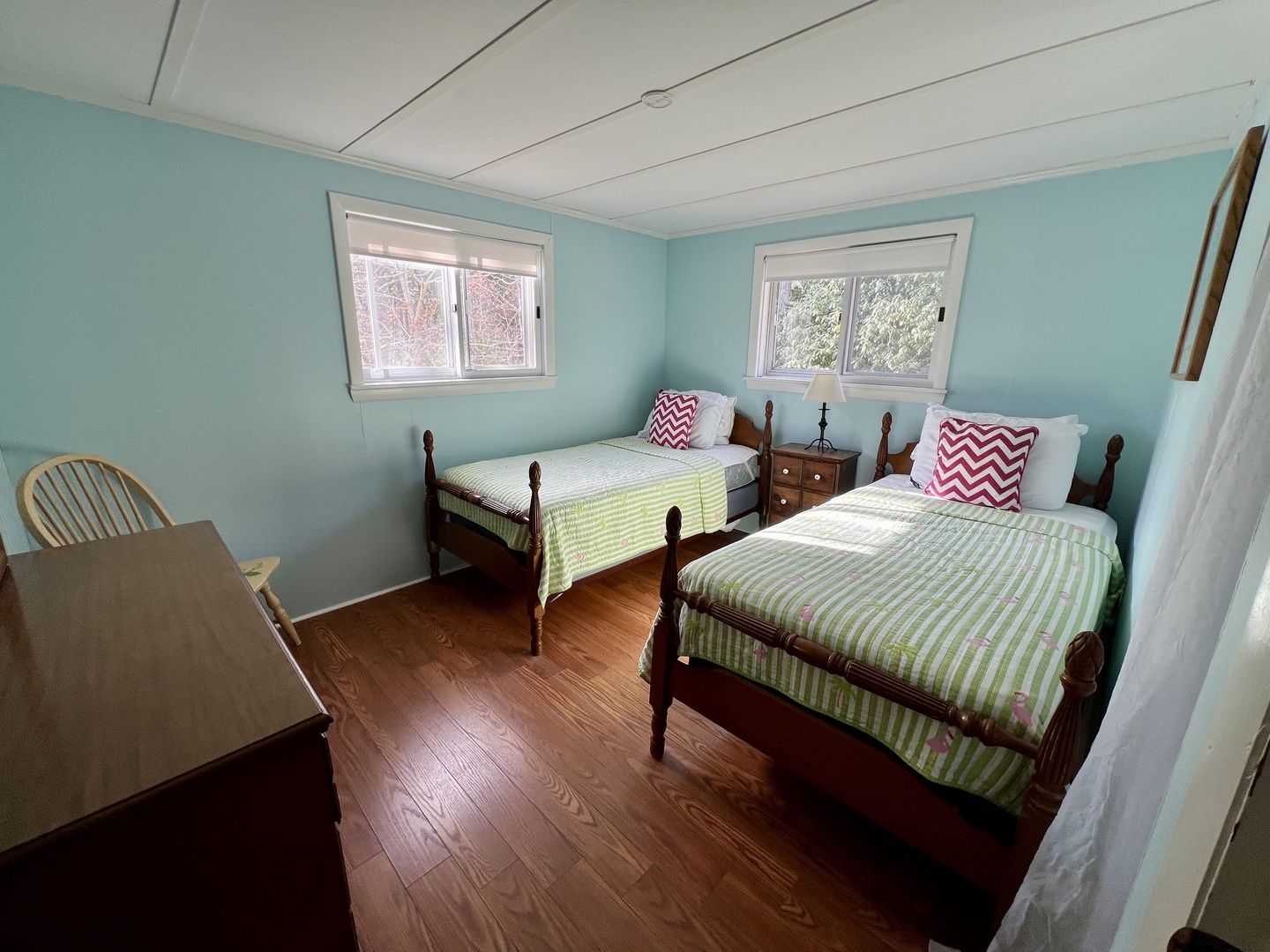 Your tranquil twin bedroom features classic wood furnishings, cheerful striped bedding, and calming blue walls that create a peaceful retreat.