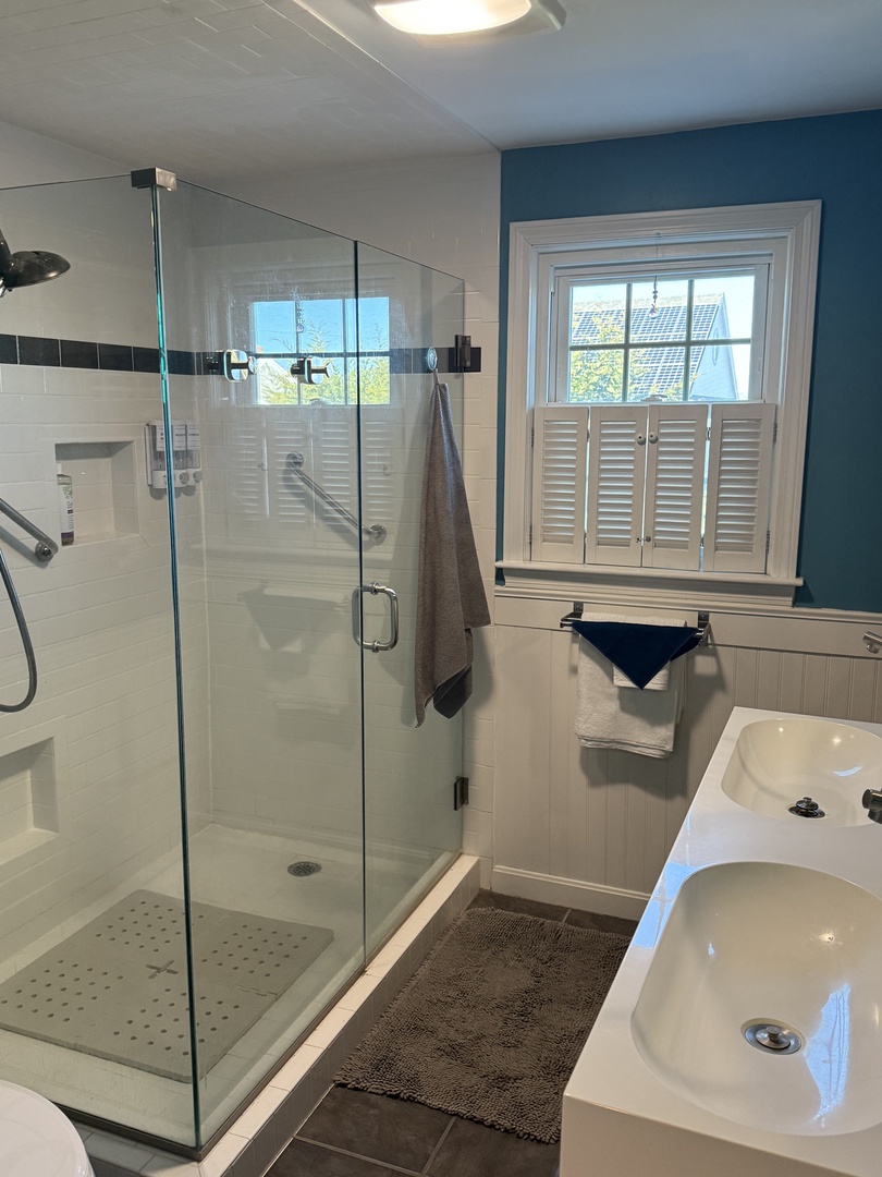 Step into your private spa-style bathroom featuring a luxurious soaking tub and rainfall shower behind elegant glass doors.