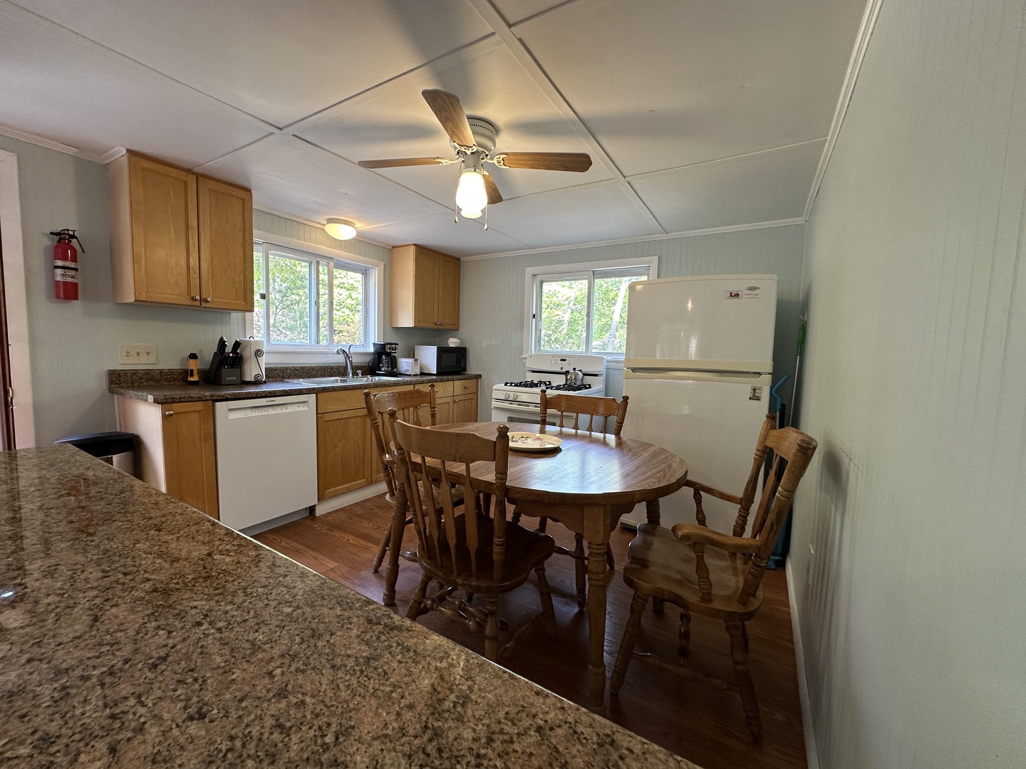 Your fully equipped kitchen and dining space offers everything needed for home-cooked meals, with warm wood furnishings and granite countertops creating a welcoming atmosphere.