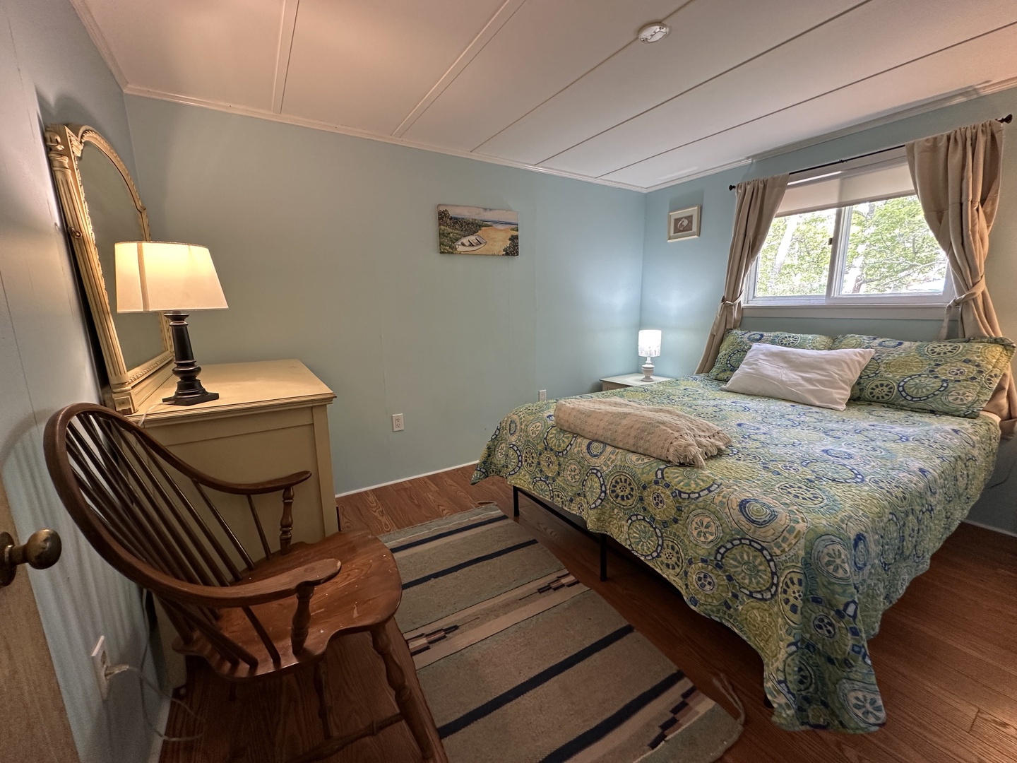 Unwind in your peaceful bedroom with cozy blue walls and a comfortable bed adorned with beautiful patterned linens.