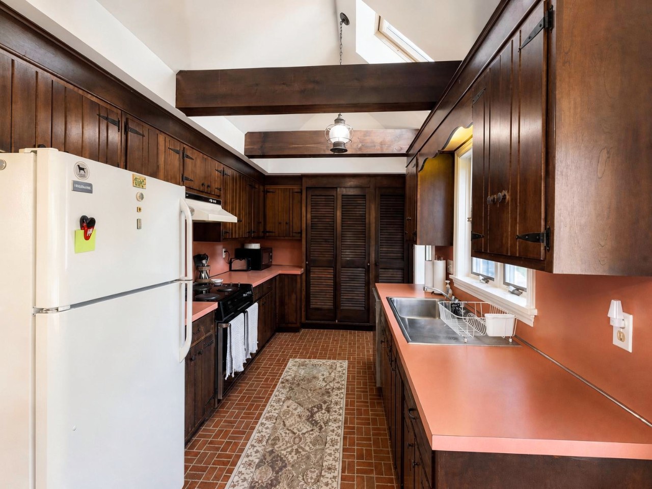 Your fully equipped kitchen features rich wood cabinetry, generous counter space, and exposed beams that add rustic charm. Cook your favorite meals with modern appliances and natural light from skylights above.