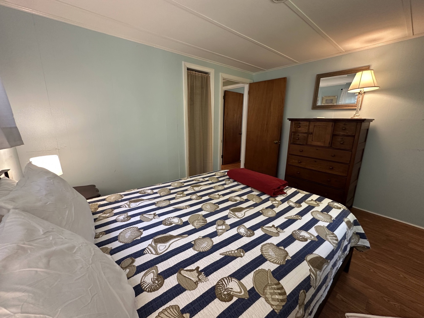 Your peaceful bedroom features a comfortable bed with nautical-themed linens, warm wood furniture, and soft lighting for restful nights.