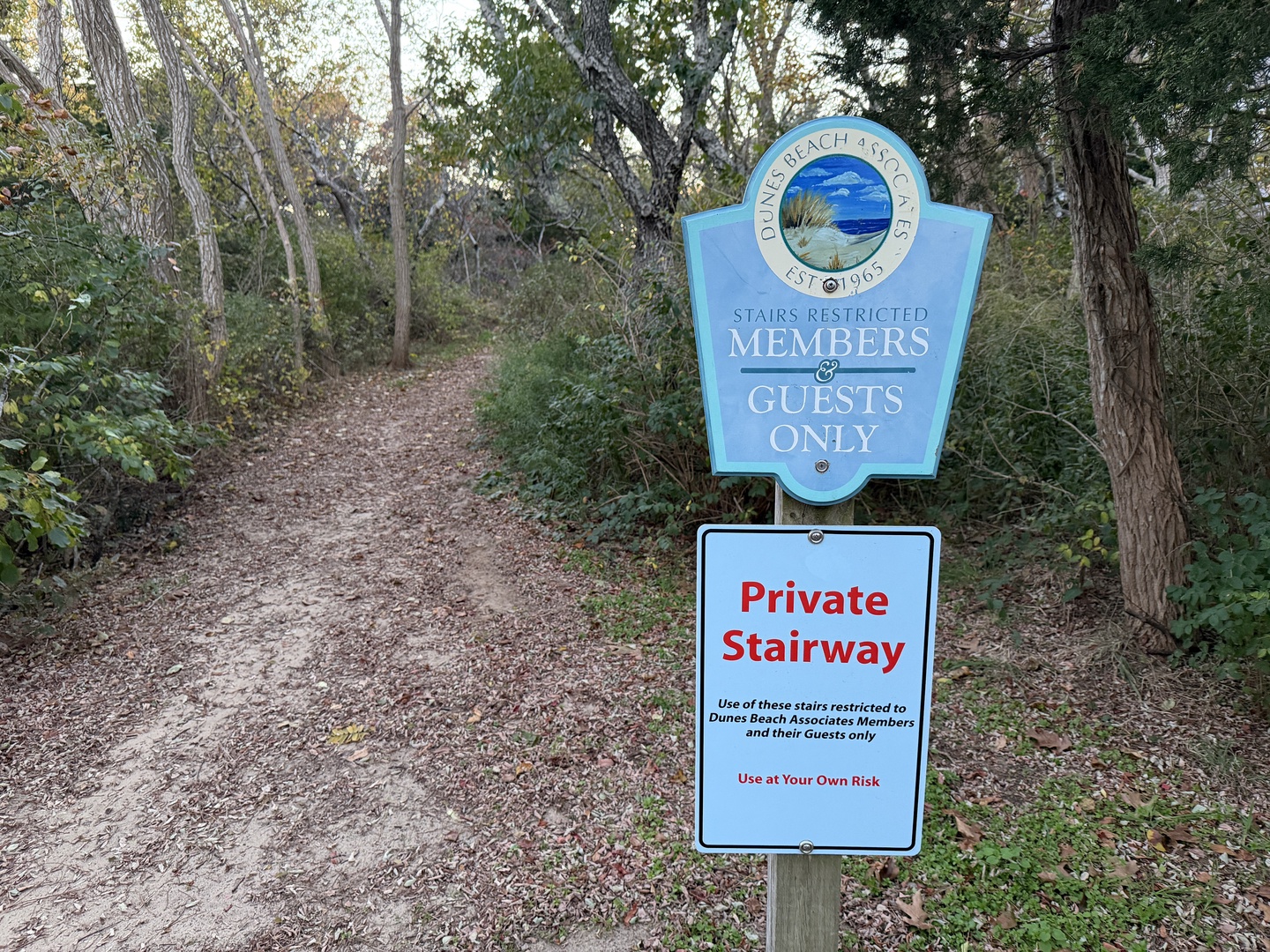 Private beach access pathway leads through wooded dunes to exclusive shoreline for members and guests only.