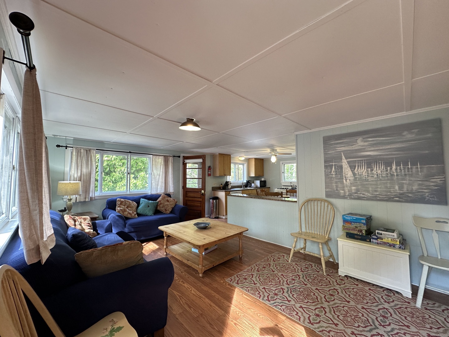 Relax in your bright coastal living space with nautical charm—plush navy seating, warm wood tones, and sailing artwork create the perfect seaside retreat.