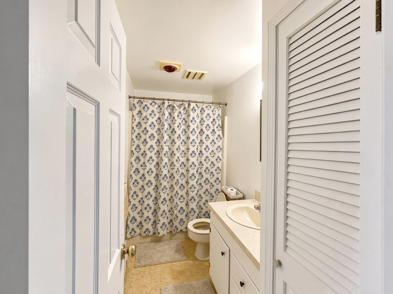 Step into your private bathroom featuring a refreshing shower, toilet, and sink. The patterned curtain and warm tones create a cozy, welcoming space for you.